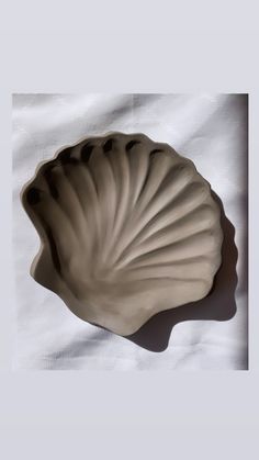 a shell shaped bowl sitting on top of a white sheet