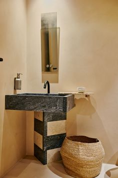 a bathroom with a sink and mirror next to a basket on the floor in front of it