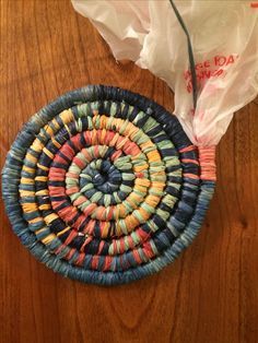 a woven basket sitting on top of a wooden table next to a white plastic bag