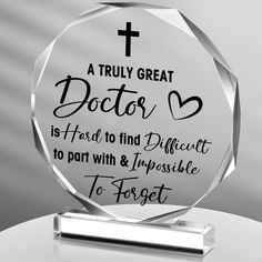 a clear glass award with a cross on the top and words below it that read, a truly great doctor is first to find difficult to