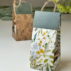 two paper bags with flowers and leaves on them