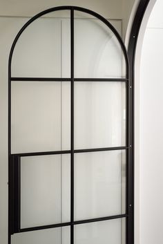 an arched glass door with white walls and black frame