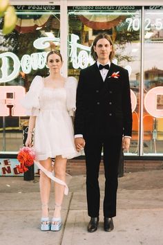 a man and woman standing next to each other in front of a store