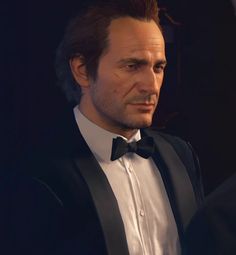 a man in a tuxedo and bow tie looking at another man wearing a suit