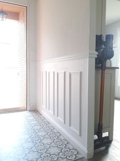 an empty room with a tile floor and white paneling on the wall next to a door