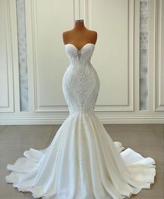 a white wedding dress on a mannequin in front of a wall and floor