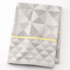 two folded gray and yellow napkins sitting on top of a white tablecloth covered in grey and yellow geometric designs