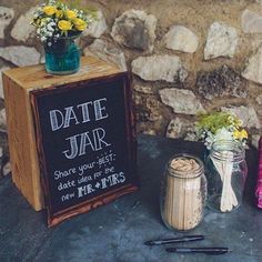 a table topped with jars filled with flowers next to a chalkboard sign that says date jar