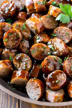 a pan filled with cooked sausages covered in sauce and garnished with parsley