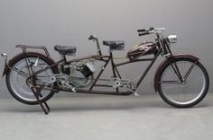 an old fashioned motorcycle is parked against a gray wall with no one on it's seat