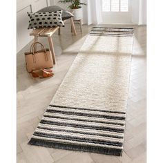 a white and black runner rug on the floor in front of a window with a handbag next to it