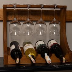 several wine glasses are lined up on a wooden rack, with one empty glass in the middle