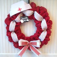 a red wreath with white ribbon and a nurse's hat hanging on the front door