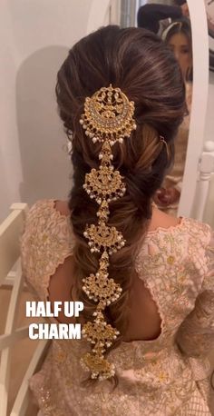 the back of a woman's head with hair in a braid and gold jewelry