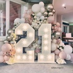 the number twenty seven surrounded by balloons and flowers is displayed in front of a window