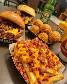 several different types of food are sitting on the table in front of sodas and burgers