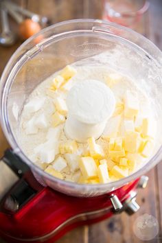 a food processor filled with cheese on top of a wooden table