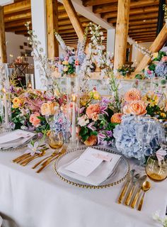 the table is set with flowers and place settings