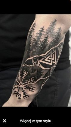 a man's arm with an image of trees, mountains and arrows on it