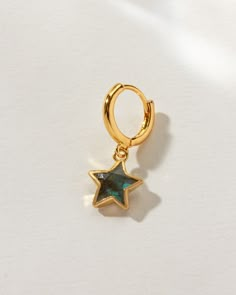 Featuring a unique star-shaped gemstone cradled in a golden embrace, this earring dangles from a huggie hoop, offering more than just ornamentation—it's a call to express your distinct style. A versatile addition to any collection, it empowers you to mix, match, and stack, crafting a look that's entirely your own. It's the perfect piece for those who draw inspiration from the celestial wonders above or the marine mystery below. Queer Earrings, Gold Earring Stack, Earring Stacks, Gold Huggie Earrings, Jewelry Tattoos, Earring Stack, Colored Earrings, Celestial Earrings, Vintage Earring