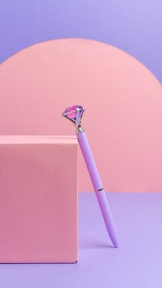 a pink pen sitting on top of a pink box next to a purple and white object