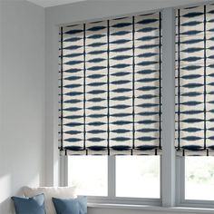 a living room with two windows covered in blue and white curtains next to a couch