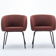 two brown chairs sitting side by side in front of a white wall with black legs