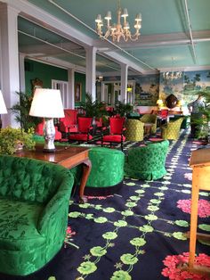 a room filled with lots of green chairs and tables next to lamps on chandeliers