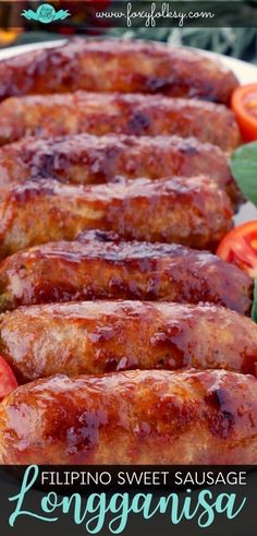 some sausages are on a plate with tomatoes and lettuce in the background