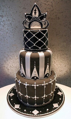 a three tiered cake decorated with black and white stripes, crowns, and beads