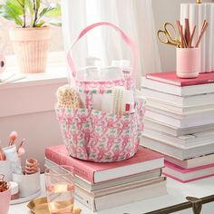 a pink and white purse sitting on top of a pile of books next to a window