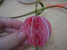 a hand holding a red and white ornament