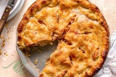 a pie sitting on top of a white plate next to a knife and fork with a slice missing