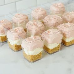 small cupcakes with pink frosting on top are arranged in clear containers for display