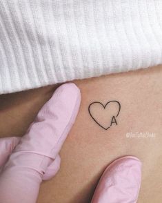 a woman's stomach with a small heart tattoo on the side of her belly