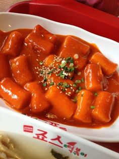 there is a bowl of food with sauce and chopsticks next to it on the table