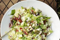 a white plate topped with lettuce and other vegetables next to a wooden table