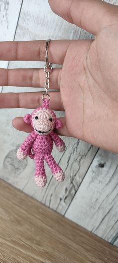 a small pink monkey keychain hanging from a persons hand