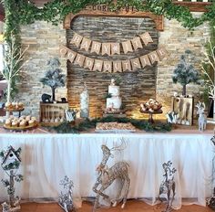 a table topped with cakes and desserts covered in greenery next to a brick wall