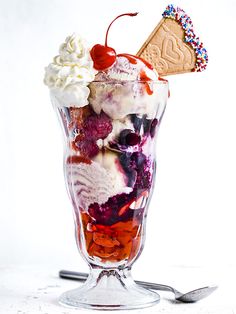 an ice cream sundae with berries, whip cream and sprinkles