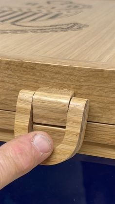 a hand is touching the bottom of a wooden box