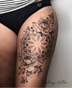 a woman's thigh with flowers and leaves on the side, in black and white