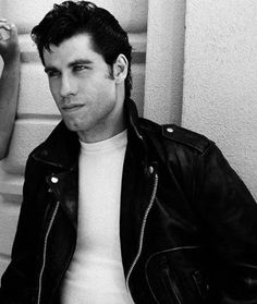 black and white photograph of a man in a leather jacket leaning up against a wall