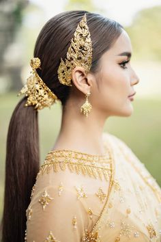 a woman with long hair in a ponytail wearing gold jewelry and an intricate headpiece