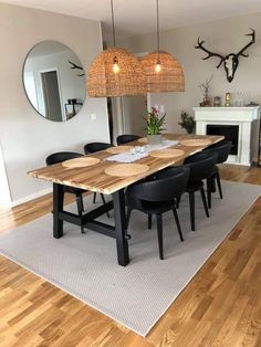 a dining room table with black chairs in front of a fire place and a mirror on the wall