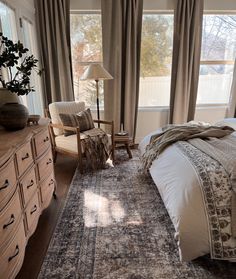 a bedroom with a bed, dresser and chair in front of a large open window