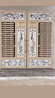 two doors with decorative designs on them in front of a wall and window sill