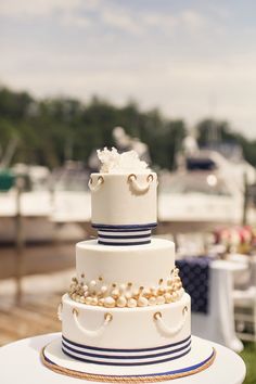 a three tiered cake sitting on top of a white table next to a boat