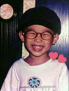 a young boy wearing glasses and a hat with hearts on the front of his shirt