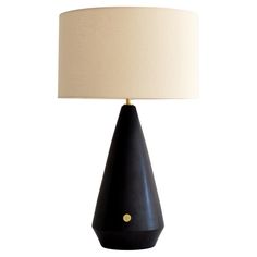 a black table lamp with a white shade on it and a gold dot in the middle